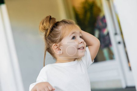 Porträt eines fröhlichen Kleinkindes im weißen T-Shirt, das im Freien wegschaut 