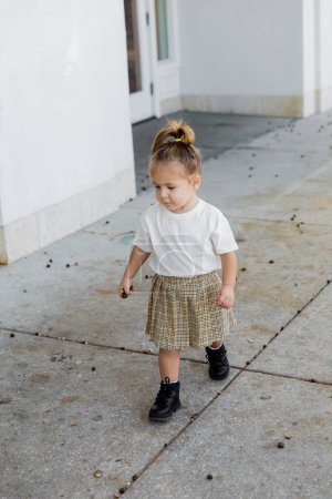 full length of toddler girl in skirt and white t-shirt walking on street in Miami 