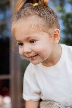Porträt eines fröhlichen Mädchens im weißen T-Shirt, das lächelt und wegschaut 