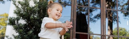 Téléchargez les photos : Petite fille positive en t-shirt blanc applaudissant les mains près d'un café extérieur à Miami, bannière - en image libre de droit