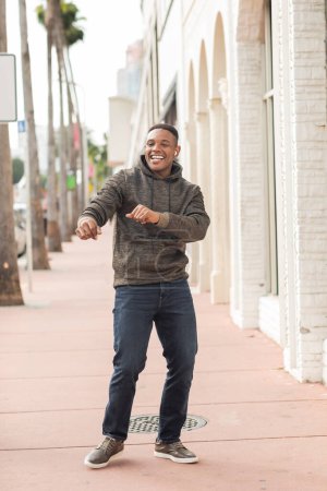 glücklich afrikanisch-amerikanischer Mann mit drahtlosem Kopfhörer hat Spaß auf der Straße in Miami 