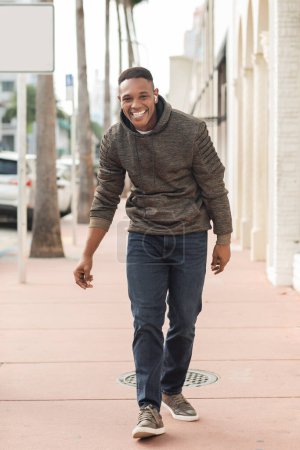 überglücklicher afrikanisch-amerikanischer Mann mit drahtlosen Kopfhörern auf der Straße in Miami 