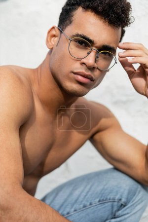 Portrait of sexy and muscular cuban man in stylish round-shaped eyeglasses 