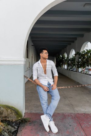 Volle Länge des stilvollen jungen kubanischen Mannes im Hemd und der stylischen runden Brille in Miami