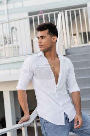 Téléchargez les photos : Homme cubain en chemise blanche et jeans regardant loin sur la rue urbaine à Miami - en image libre de droit