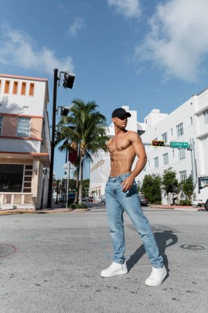 Téléchargez les photos : Cuban man with athletic body in baseball cap and blue jeans on street in Miami, south beach - en image libre de droit