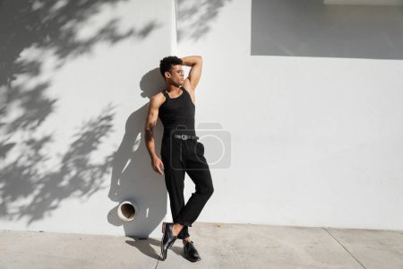 Téléchargez les photos : Homme cubain sexy en lunettes et t-shirt noir sans manches posant près du mur à Miami, pendant l'été - en image libre de droit