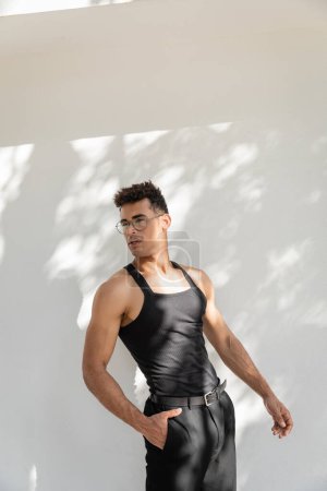 Téléchargez les photos : Jeune homme cubain à la mode et beau en lunettes de soleil et tenue noire posant à Miami - en image libre de droit