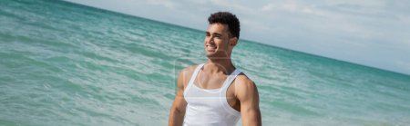 Muscular cuban young man walking ocean water of Miami South Beach, Florida, banner