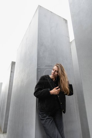 femme aux cheveux blonds touchant les cheveux et regardant loin près du Mémorial aux Juifs assassinés d'Europe à Berlin
