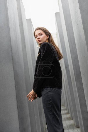 Portrait of young woman in jacket looking at camera between Memorial to Murdered Jews of Europe