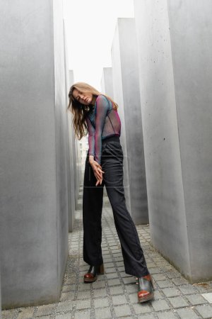 Photo for Full length of fashionable fair haired woman standing between Memorial to Murdered Jews of Europe - Royalty Free Image