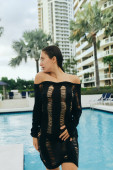 luxury resort, sexy brunette woman with tanned skin and wet hair posing in black knitted dress, standing near outdoor swimming pool in Miami, summer getaway, hotel building, palm trees  t-shirt #658655818