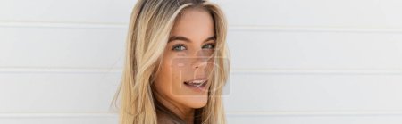 Téléchargez les photos : Une jeune et belle femme aux longs cheveux blonds sourit joyeusement sous le soleil de la plage de Miami. - en image libre de droit