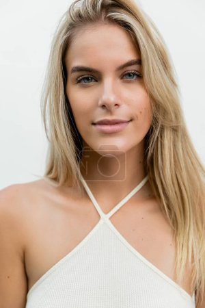 Foto de A young and beautiful blonde woman with long hair elegantly posing in a white top under the Miami sun. - Imagen libre de derechos