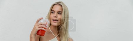 Téléchargez les photos : Une jeune, belle femme blonde à Miami tenant une tasse rouge tout en portant une robe blanche fluide - en image libre de droit