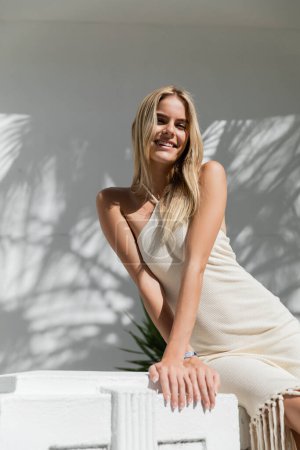 Eine junge und schöne blonde Frau in einem weißen Kleid posiert an einem sonnigen Tag in Miami für ein Foto.
