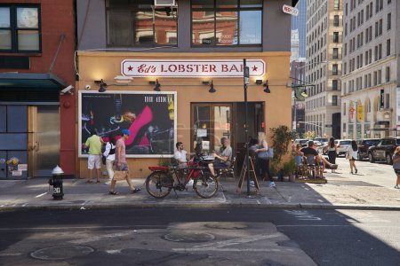 Photo for NEW YORK, USA - NOVEMBER 26, 2022: eds lobster bar, bicycle and pedestrians on walkway in soho - Royalty Free Image