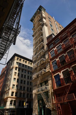 low angle view of tall building with fire escape stairs on avenue of autumnal new york city