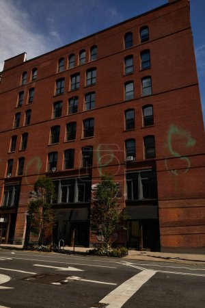 Téléchargez les photos : Bâtiment en brique rouge près des arbres et une large route dans le centre-ville de New York, paysage urbain automnal - en image libre de droit