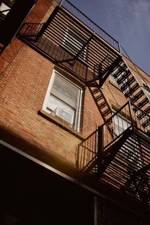 vista de ángulo bajo del edificio de ladrillo con escaleras de escape de incendios en la ciudad de Nueva York, arquitectura urbana