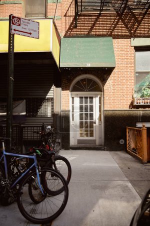 moderne Fahrräder in der Nähe des Wohnhauseingangs an der gemütlichen Straße in New York City, Charme der Stadt