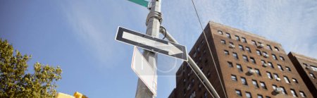 vista de ángulo bajo del poste de la calle con señales de tráfico cerca del edificio de ladrillo rojo en Nueva York, bandera