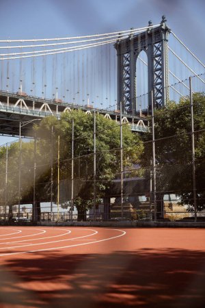 Foto de Vista panorámica del puente Manhattan cerca de árboles otoñales y estadio al aire libre en la ciudad de Nueva York - Imagen libre de derechos