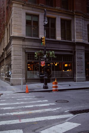 Straßenmast mit Ampeln und Blumentöpfen in der Nähe eines Gebäudes mit Restaurant in New York City