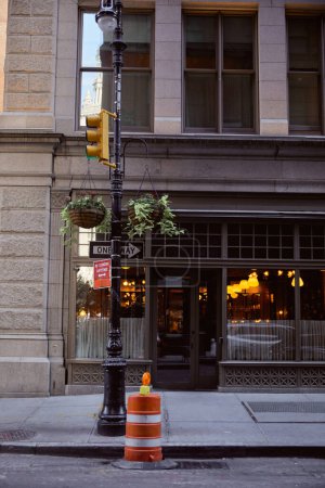 building with restaurant near street pole with traffic lights and flowerpots in new york city