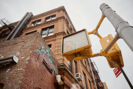 low angle view of street pole with traffic lights near brick buildings on street in new york city