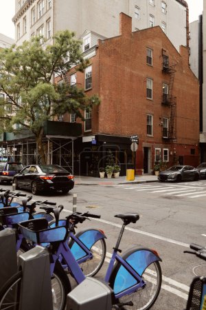bike parking and cars moving on crossroad on downtown avenue in new york city, autumnal scene