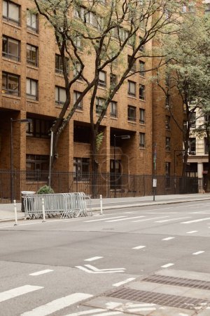szeroka jezdnia przy ceglanym budynku i jesiennych drzewach w Nowym Jorku, ulica Metropolis
