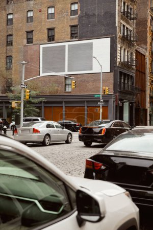 Foto de Edificio de ladrillo con plazas pintadas cerca de la carretera con el tráfico en movimiento en la avenida de la ciudad de Nueva York - Imagen libre de derechos