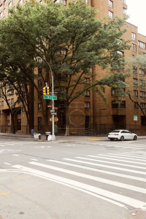Herbstbäume und Backsteingebäude nahe Verkehrskreuzung mit Fußgängerüberweg in New York City