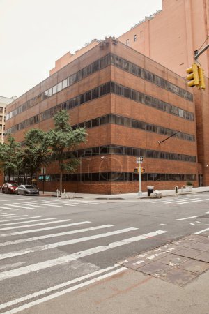nowoczesny murowany budynek na skrzyżowaniu z przejściem dla pieszych na miejskiej ulicy Nowego Jorku
