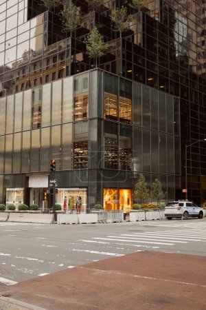 edificio moderno con fachada de vidrio y tienda de ropa en cruce en avenida en la ciudad de Nueva York