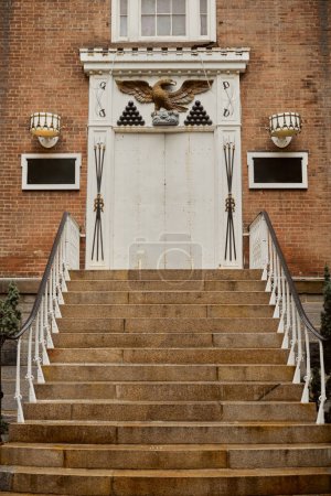 brick building with white decorated door and stone stairs in new york city, urban architecture