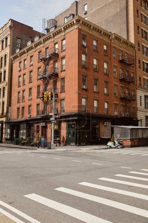 red brick building with storefront and fire escape stairs on crossroad in new york city, streetscape