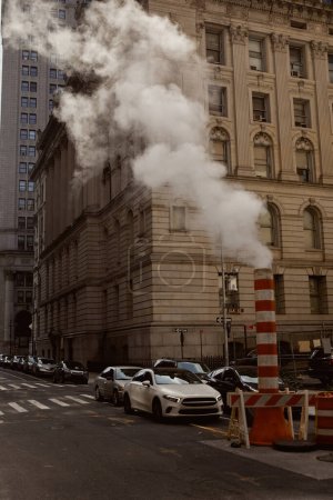 New York City Straßenbild mit Fahrzeugen, die sich auf der Fahrbahn in der Nähe von Dampfleitungen bewegen, urbane Atmosphäre