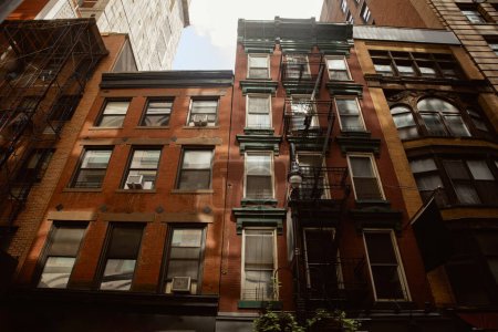 vintage red brick house with fire escape stairs in downtown of new york city, urban architecture