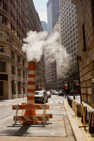 Téléchargez les photos : Tuyau de vapeur sur la rue urbaine avec des véhicules se déplaçant sur la chaussée du centre-ville de New York, scène urbaine - en image libre de droit