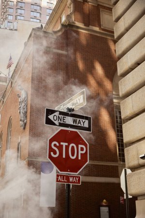 Foto de Señales de tráfico cerca de vapor y edificios antiguos en la calle de la ciudad de Nueva York, entorno urbano escena - Imagen libre de derechos