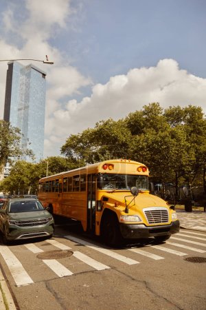 Téléchargez les photos : Autobus scolaire jaune et voitures sur le passage supérieur près des arbres avec feuillage d'automne le long de la chaussée dans la ville de New York - en image libre de droit