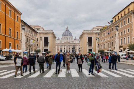 Foto de Vaticano, Vaticano - 29 de diciembre de 2023: Vista de la calle Conciliación frente a la Basílica de San Pedro en la Plaza de San Pedro (Plaza de San Pedro) donde los turistas caminan en un día de invierno - Imagen libre de derechos