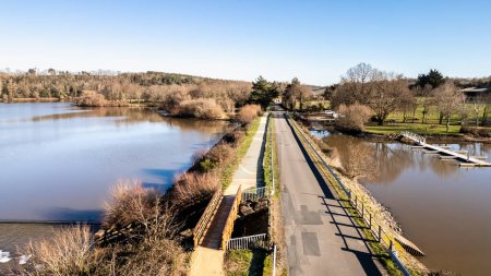 Bridge passing over the Jaunay lake in aerial drone view at Chapelle-Hermier, France on a sunny winter day