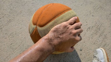 A hand is touching a basketball concrete floor 