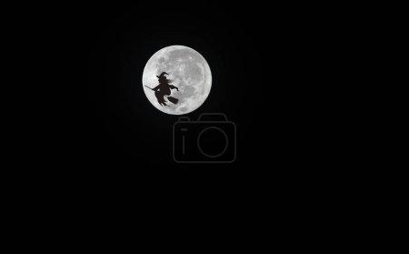 Photo for A witch and her broomstick is flying and transit the moon in background (Halloween night) - Royalty Free Image