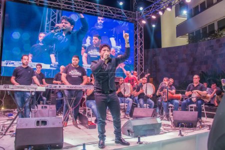 Téléchargez les photos : Tente du Ramadan Spectacle musical. Le chanteur Moustafa Hagag et le groupe de musique sur scène. La photo est mise au point sélective avec une faible profondeur de champ. Prise au Caire Égypte le 22 mai 2018 - en image libre de droit