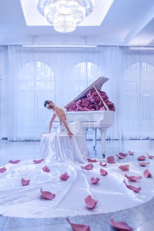 Téléchargez les photos : Belle femme avec piano blanc et pivoines fleurs en studio blanc - en image libre de droit